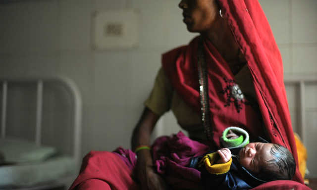 A new born baby sleeps in the arms of her mother at a Community Health Center in Mall, near Lucknow, India. [Photograph: Roberto Schmidt]